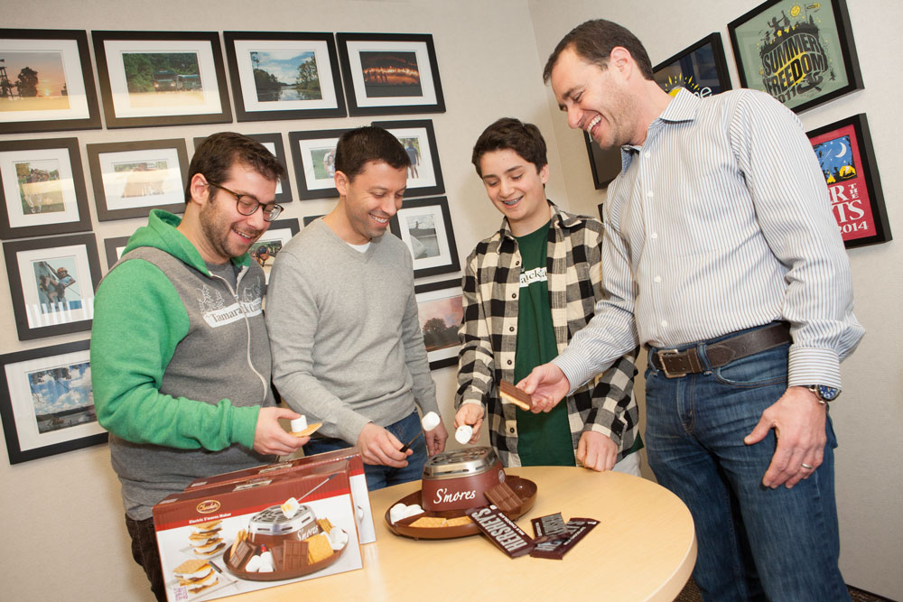 Caption for the group shot: Breaking out a closely-guarded stash of Hershey’s chocolate in the Tamarack Camps office in the Max M. Fisher Federation Building Ryan Findling demos the Nostalgic Electric s’more maker for taste-testers, Gabe Neistein, Jason Charnas and Lee Trepeck.